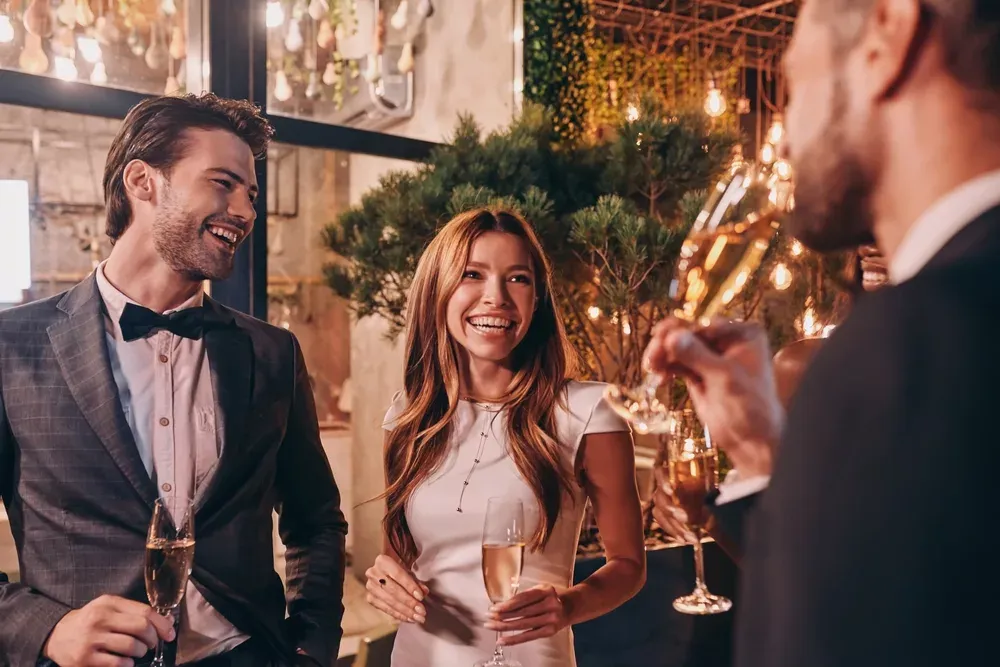 Pareja elegante riendo con copas de champán en una celebración nocturna (imagen ilustrativa)